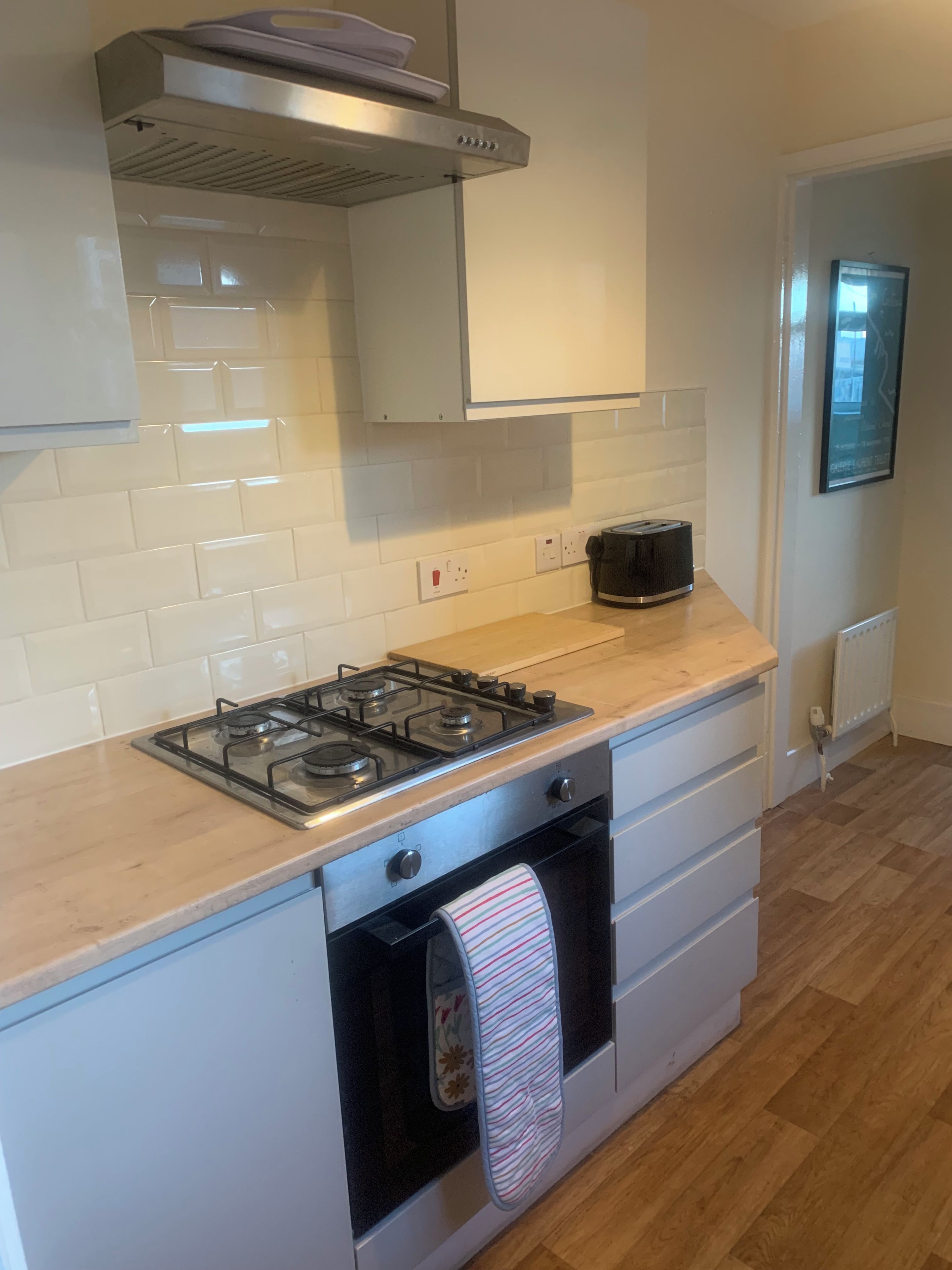 A kitchen with a gas stove, oven, and a toaster on the countertop.