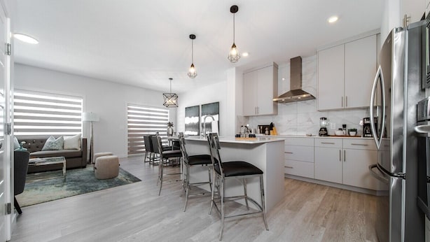 A modern kitchen with white cabinets, stainless steel appliances, and pendant lighting. - Modern Executive Home-Sleeps12-KingBeds-FullHouse (Edmonton)