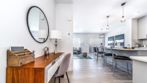 A modern kitchen with a bar area, a wooden desk with a mirror, and a seating area with a view. - Modern Executive Home-Sleeps12-KingBeds-FullHouse (Edmonton)