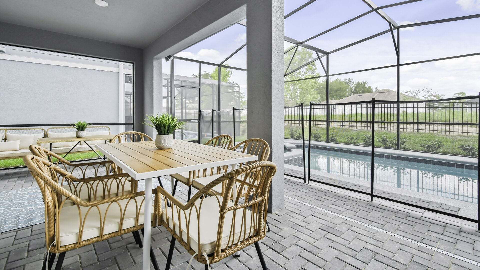 A covered patio with a pool, wicker furniture, and a view of the outdoors.