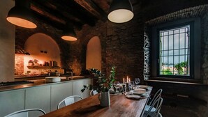 A rustic kitchen with a wooden island, stone walls, and a large window.
