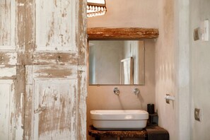 A bathroom with a rustic wooden door, a white sink, and a mirror above it.