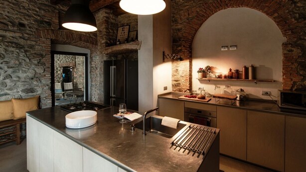 A kitchen with a central island, stone walls, and hanging pendant lights.