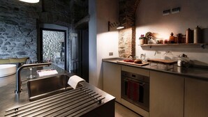 A modern kitchen with a stone wall, stainless steel appliances, and a wooden countertop.