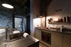 Eine moderne Küche mit Steinwand, Edelstahlgeräten und Arbeitsplatte aus Holz.