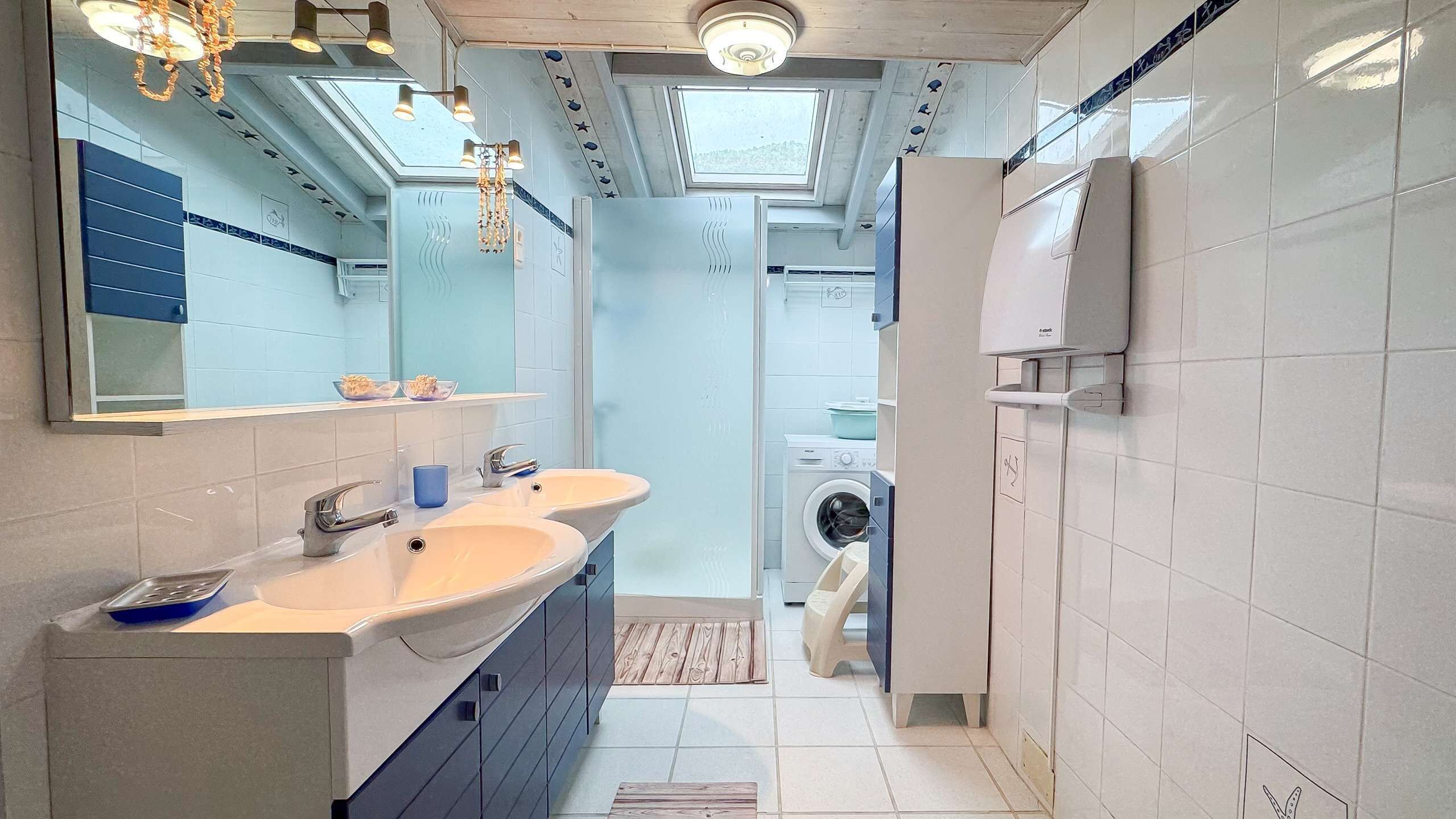 Un baño moderno con lavamanos dobles, un espejo grande y un tragaluz en el techo.