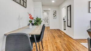 Un comedor moderno con una mesa de madera, sillas negras y un jarrón con flores.