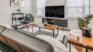 Una sala de estar moderna con sofá, mesa de centro, televisor y estantería.