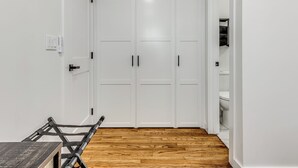 Una habitación con paredes blancas, suelo de madera y un armario blanco de dos puertas.
