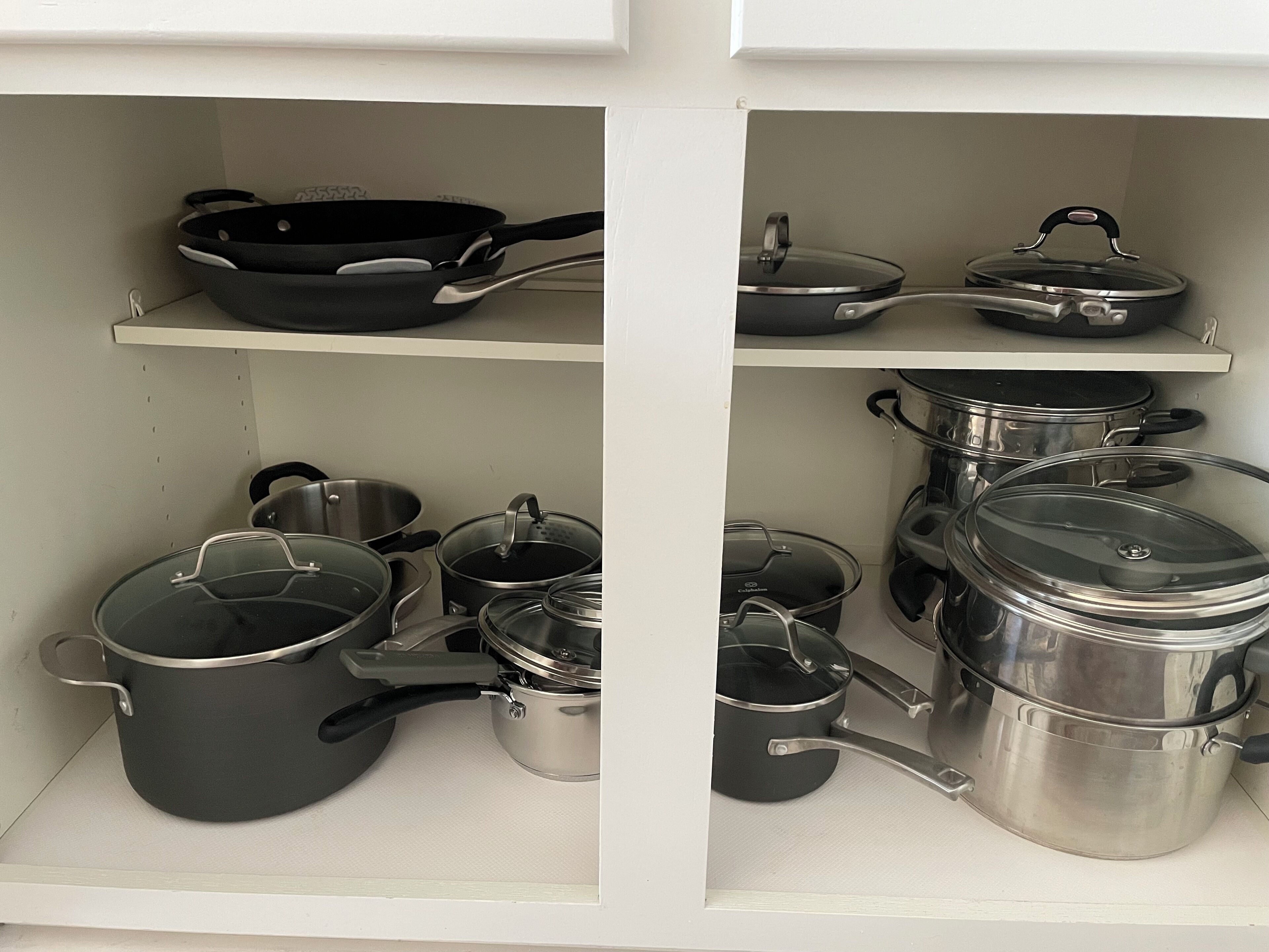 Un armario de cocina con diferentes ollas y sartenes.