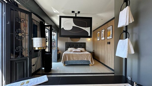 A modern hotel room with a large bed, a bathtub, and a TV mounted on the wall. - Luxury apt with jacuzzi near downtown  (Santa Rosa de Cabal)