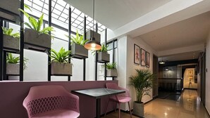 A modern interior with a seating area featuring two pink chairs and a table, a potted plant, and a hanging light fixture. - Luxury apt with jacuzzi near downtown  (Santa Rosa de Cabal)