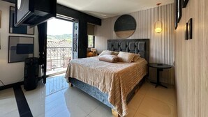 A modern bedroom with a large bed, a TV mounted on the wall, and a balcony with a view. - Luxury apt with jacuzzi near downtown  (Santa Rosa de Cabal)