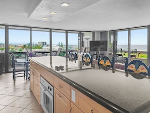Kitchen and open living area from alternate angle showcasing panoramic water views through large windows - Beautiful and Updated 4th Floor Condo at Beach Terrace (Siesta Key)