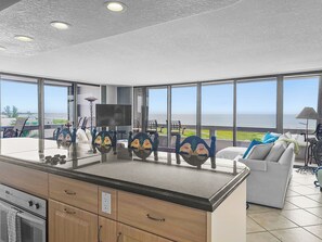 Open-plan kitchen and living area with floor-to-ceiling windows offering sweeping Gulf water views