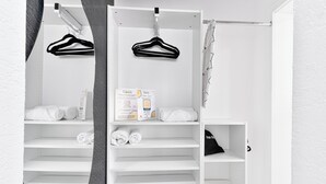 A white closet with shelves, a hanging rod, and a folded towel on the bottom shelf.