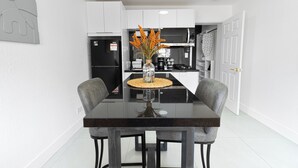 A modern kitchen with white cabinets, a black countertop, and a dining table with four chairs.