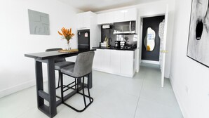A modern kitchen with white cabinetry, a black refrigerator, and a dining area with a table and two chairs.
