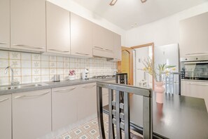 A modern kitchen with light-colored cabinets, a stainless steel sink, and a dining area with a table and chairs. - GuestHost - 85 sqm apartment for 6 people, located on the first floor of a building with an elevator (not suitable for people with disabilities). It features two balconies and is situated in a very quiet neighborhood, just steps from Parco Dora, full of  (Torino)