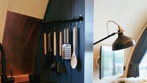 A kitchen with dark blue cabinets, a wooden countertop, and a hanging utensil rack.