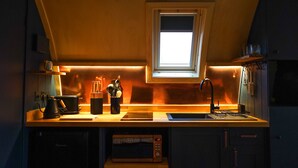 A compact kitchen with a window, a sink, a stove, and a microwave.