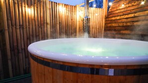 A hot tub surrounded by wooden walls and string lights.
