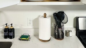 A kitchen with a wooden cabinet containing white bowls and plates, a roll of paper towels, and a dish rack. - 4BR Summer Home For 10ppl with Game Room -White Mtns! (Woodstock)