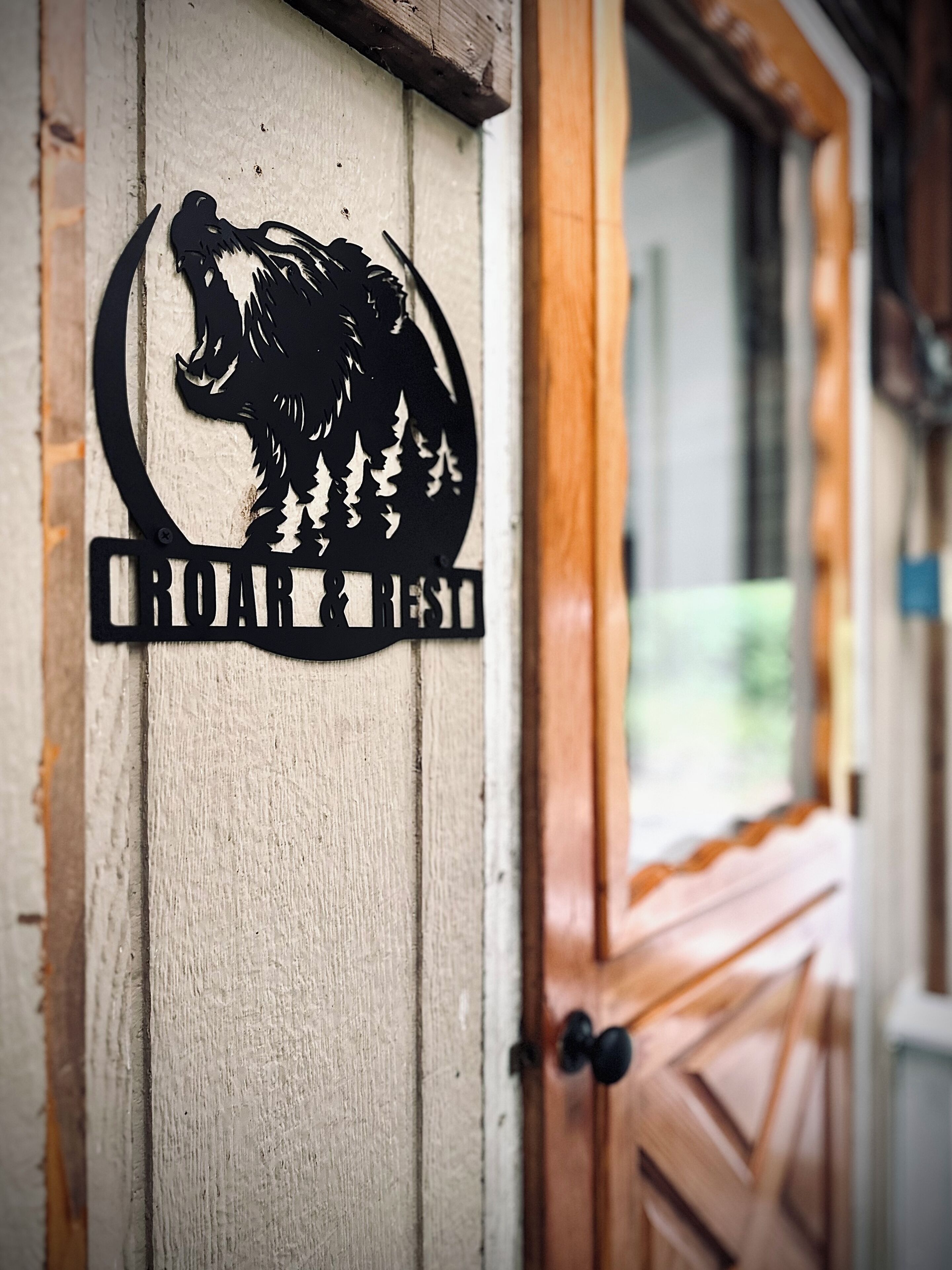 Eine Holztür mit einem Bärenlogo und der Aufschrift 'ROAR & REST'.