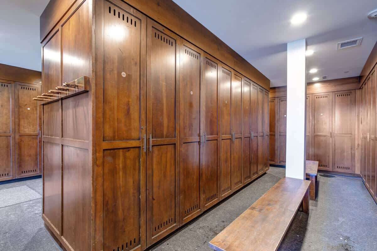 A locker room with wooden lockers, a bench, and a white pillar.