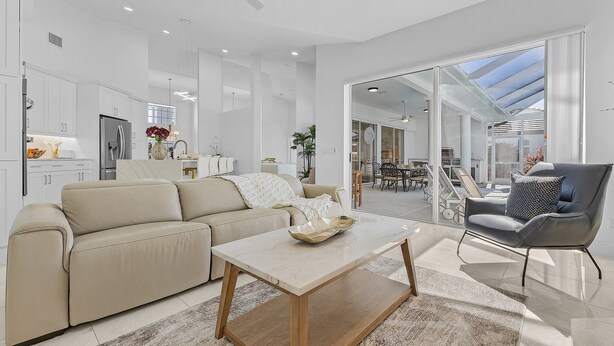 Een moderne woonkamer met een beige bank, een houten salontafel en een zwarte leren fauteuil.