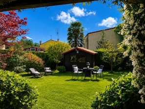 A well-maintained garden with a small wooden structure, a lawn, and a variety of plants.