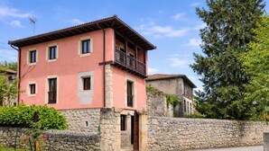 A two-story building with a stone wall and a balcony. - La Curuxa House in Vidiago, Llanes (Vidiago)