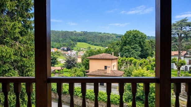 A view from a balcony with a railing, overlooking a rural landscape with houses, greenery, and a clear sky. - La Curuxa House in Vidiago, Llanes (Vidiago)