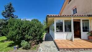 Ein Haus mit verblendetem Balkon, einem Kiesweg und einem Garten mit Nadelbäumen.