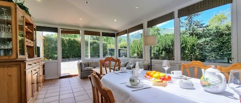 Un comedor con una mesa lista para dos personas, rodeado de grandes ventanales que ofrecen vistas al follaje.