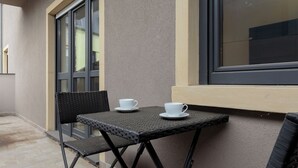 A small outdoor seating area with a table and two chairs, a window, and a door. - GIORGIA 11-Large Double Room (Dudelange)