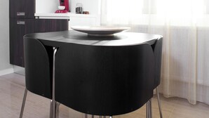 Una cocina moderna con una mesa de comedor redonda, sillas negras y una cafetera.