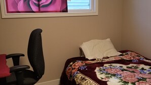 A bedroom with a bed, a desk, a chair, a window with blinds, and a floral painting on the wall. - For a professional Room in NW Calgary (Calgary)