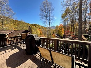 A wooden deck with outdoor furniture and a barbecue grill.