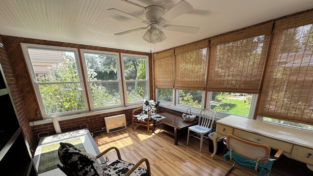 A sunlit room with a ceiling fan, large windows, a wooden floor, and a desk with a chair. - Charming 3-bedroom apartment in serene Grosse Pointe Park, close to lake (Grosse Pointe Park)