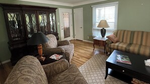 A living room with patterned sofas, a coffee table, a lamp, and a window with blinds. - Charming 3-bedroom apartment in serene Grosse Pointe Park, close to lake (Grosse Pointe Park)