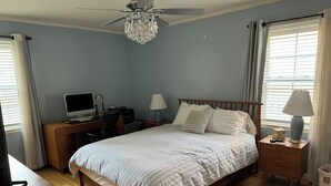 A bedroom with a bed, a desk with a computer, a ceiling fan, and a window with curtains. - Charming 3-bedroom apartment in serene Grosse Pointe Park, close to lake (Grosse Pointe Park)