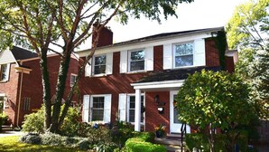 A two-story brick house with a front porch, a mailbox, and a well-maintained garden. - Charming 3-bedroom apartment in serene Grosse Pointe Park, close to lake (Grosse Pointe Park)