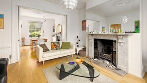 Amplia sala de estar con chimenea, un sofá blanco y una mesa de centro de vidrio.