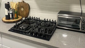 A kitchen with a Black & Decker toaster oven, a stove, and a microwave above it. - Unique container home  (El Cajon)