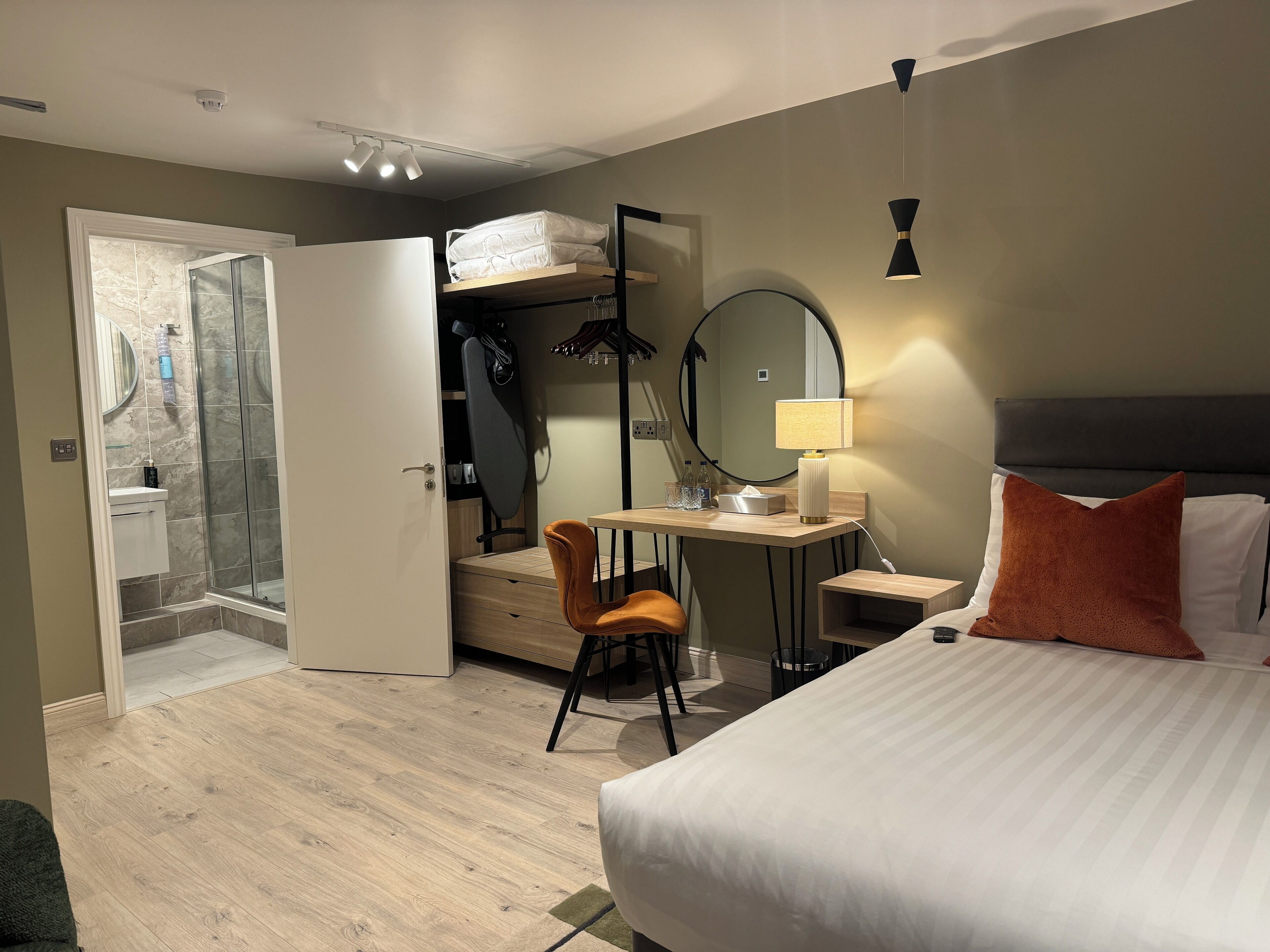 Une chambre d’hôtel comprenant un lit, un bureau avec une chaise, un miroir, une lampe et une armoire.
