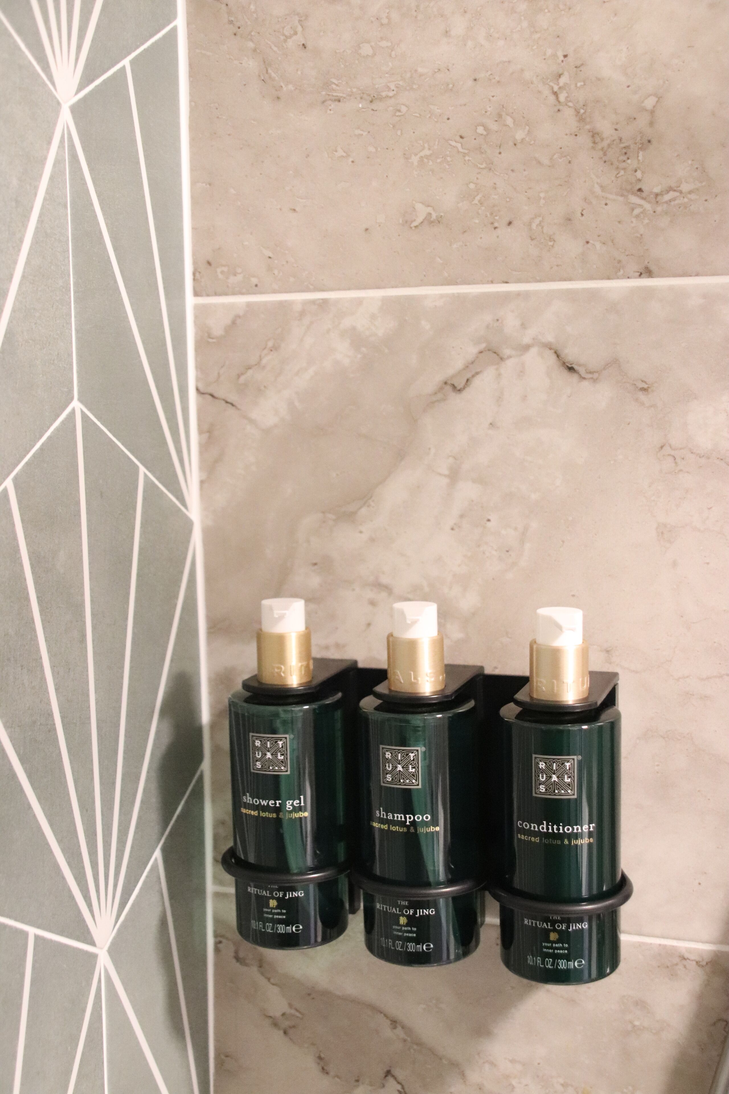 Three bottles of Ritual of Jing products on a tiled wall.