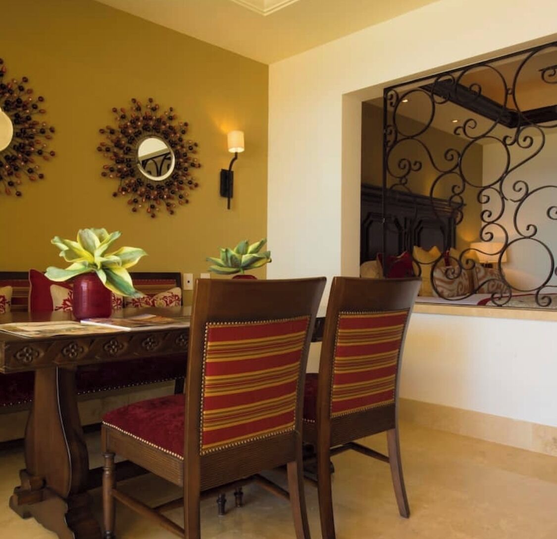 A dining area with a wooden table, striped chairs, and decorative wall mirrors.