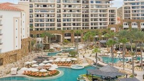 Un hôtel à plusieurs étages, doté d’une piscine centrale et d’espaces extérieurs aménagés pour se détendre.