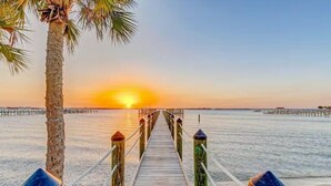 A wooden pier leading to a beach with a sunset in the background. - Beachside Deluxe: Endless Amenities + Private Pool! 🌴 (Melbourne Beach)